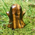 Polished tiger eye stone ghost figurine carving on green moss for Halloween decor - Tiger's Eye