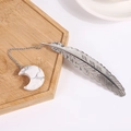 Silver feather metal bookmark featuring a white marble moon stone pendant on a wood tray - Howlite