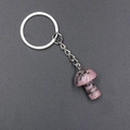 Pink rhodonite mushroom keychain with silver metal ring on dark textured background - Rhodonite