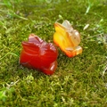 Carved carnelian crystal rabbit figurines set on natural moss background - Red Agate