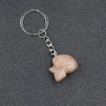 Natural sunstone skull keychain carved with silver metal ring on dark textured background - Red Aventurine