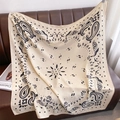 Detailaufnahme eines beigen Paisley-Halstuchs drapiert auf einem Ledersofa - 90x90cm / Beige