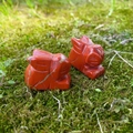 Pair of hand-carved natural red jasper bunny statues on a mossy green background - Red Jasper