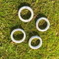 Set of 4 white turquoise rings with marble texture displayed on natural green moss - Howlite