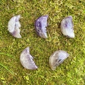 Five crescent moon face natural amethyst carvings displayed on green moss surface - Amethyst (Single Piece)