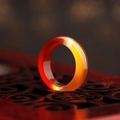 Translucent red and yellow gradient agate stone ring on a carved wooden stand - Red Agate
