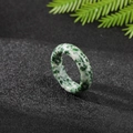 Polished natural agate ring with green spotted texture on a dark minimalist base - Qinghai Jade