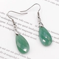 Green teardrop multifaceted gemstone earrings with silver hooks on a book page - Green Aventurine