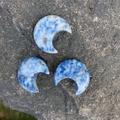 Drei halbmondförmige blaue Sodalith-Natursteine auf einer Felsoberfläche - Mini Sichelmond Blaustandstein