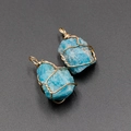 Handmade blue natural crystal pendant with gold wire wrapping on grey background - Kyanite