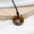 Tiger eye gemstone donut pendant with black braided cord and golden brown texture - Tiger's Eye