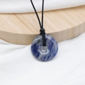 Natural Sodalite stone donut necklace with black cord on wooden display stand - Blue Sodalite