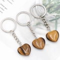 Tiger Eye heart-shaped stone keychain with silver metal ring on magazine background - Tiger's Eye