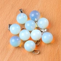 Translucent milky white opal sphere pendant with silver bail on light wood background - Synthetic Opal