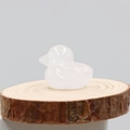 Figura de pato tallada en cuarzo rosa natural sobre una base de madera circular - Cristal de roca