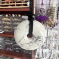 White turquoise donut pendant necklace with black braided cord and marble pattern texture - Howlite
