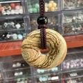 Natural wood grain stone donut pendant necklace with dark braided cord and bead - Jasper