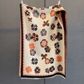 Gros plan sur l'imprimé floral du châle en maille épaisse beige avec franges - Noir