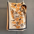 Detail of floral jacquard scarf with orange petals, black borders, and delicate fringe - Orange