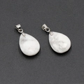 Faceted white howlite crystal teardrop pendants with silver metal bails on black background - Howlite