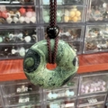 Green jade donut pendant with natural dark patterns and dark brown braided cord - Sparrow Stone
