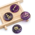 Piedras de amatista pulida con símbolos Reiki dorados sobre esterilla de bambú - Amatista