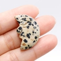Hand-carved dalmatian jasper crescent moon face stone held between fingers - Dalmatian Jasper