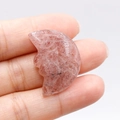 Natural strawberry quartz carved moon face stone pendant held in hand for size visualization - Strawberry Quartz