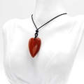 Polished 40mm natural red agate heart pendant with black cord on display - Red Jasper