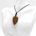 Heart-shaped Unakite natural stone pendant with a black cord necklace on a mannequin - Unakite