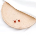 Elegante Ohrstecker mit roten Achatperlen und Silberstiften auf einem Holztablett - Roter Achat