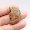 Unakite stone moon face carving showing natural green and pink mottled patterns - Unakite