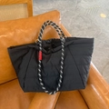 Detail der schwarzen gesteppten Tragetasche mit geflochtenen Seilgriffen auf Sofa - Klein / Schwarz