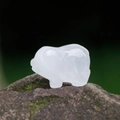 Miniature white crystal pig figurine carved from natural stone on a mossy rock - White Crystal