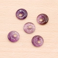 Cinco donas de amatista púrpura para joyería DIY sobre fondo de madera clara - Amatista