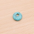 Colgante de dona de turquesa azul con vetas negras sobre fondo de madera - Turquesa Azul Sintética