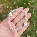 Skull punk bracelet with 8mm clear crystal beads and white skull charms held outdoors - White Crystal