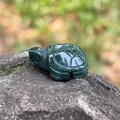 Carved dark green natural crystal turtle figurine on grey rock for desktop decor - India Agate