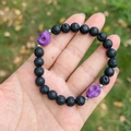 Black lava stone beaded bracelet with purple skull accents and silver spacers on hand - Lava Stone