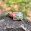 Carved unakite crystal turtle figurine with green and red mineral textures on rock - Unakite
