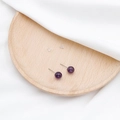 Klassische lila Amethyst-Ohrstecker mit Silberstift auf weißer Seide präsentiert - Amethyst