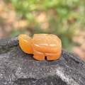 Hand-carved orange agate turtle figurine with detailed shell pattern on natural mossy rock - Topaz