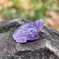 Natural purple amethyst turtle figurine carved from crystal on a dark stone background - Amethyst