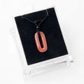Pendentif ovale en cornaline orange sur cordon noir dans une boîte d'exposition - Rouge Pastèque (Synthétique)