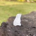 Mini natural white crystal bear figurine sitting on a rock with outdoor grass background - White Crystal