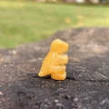 Miniature hand-carved orange jade dinosaur crystal figurine on natural stone - Topaz