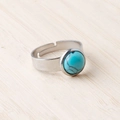 Adjustable stainless steel ring with 11mm round turquoise stone on a wooden background - Blue Turquoise (Synthetic)