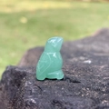Hand-carved green aventurine gemstone bird figurine displayed on a natural grey rock - Green Aventurine