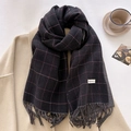 Detail of dark grey plaid scarf with fringes and white label on a cozy winter background - Black
