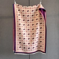Gros plan d'une écharpe jacquard beige avec motifs de chevaux rouges et fines franges - Rose